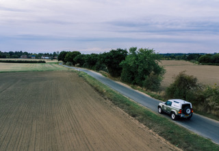 Un'auto percorre una strada di campagna presso BoerenBed Sunninglye Farm, circondata da campi nell'Est d'Inghilterra.