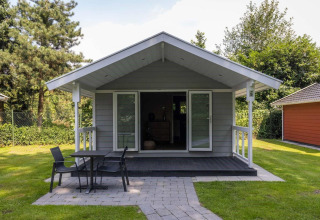 Vista frontal del Tiny House Deluxe en Holiday park Latour, Países Bajos, rodeado de césped y árboles.