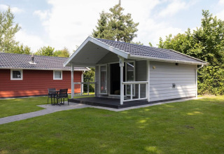 Tiny House Deluxe en Holiday park Latour en los Países Bajos, rodeada de césped y un porche cubierto moderno.