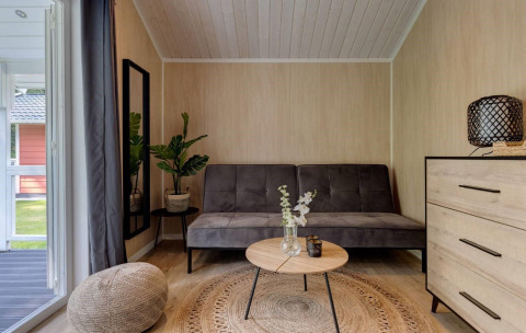 Modern living area inside Tiny House Deluxe at Holiday park Latour, Netherlands, with grey sofa.