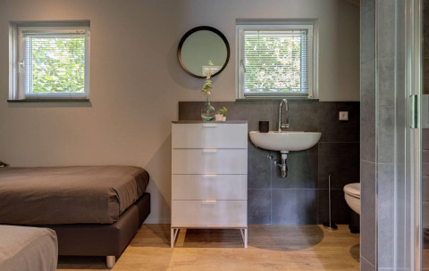 Dormitorio y baño modernos y compactos en Tiny House Deluxe en Holiday park Latour, Países Bajos.