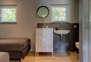 Dormitorio y baño modernos y compactos en Tiny House Deluxe en Holiday park Latour, Países Bajos.