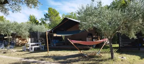 Buitensafari-tent met hangmat en picknicktafel op Camping Pian di Boccio in Italië, omgeven door bomen.