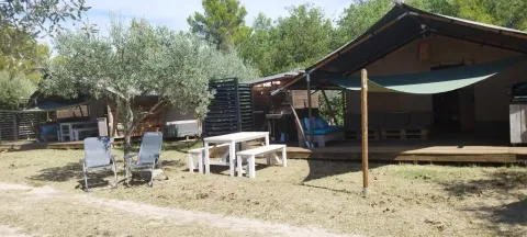 Buitenaanzicht van safaritent met badkamer op Camping Pian di Boccio in Italië, omringd door natuur.