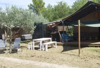Buitenaanzicht van safaritent met badkamer op Camping Pian di Boccio in Italië, omringd door natuur.
