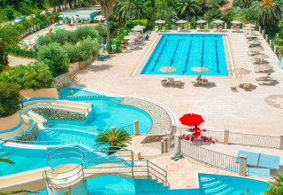 Vista de piscina, tumbonas y vegetación en Camping Rosselba Le Palme, parque vacacional en la Toscana, Italia.