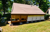 Tente safari Lodge Liberta au Camping Merendella en France, entourée de pelouse et d’arbres verdoyants.