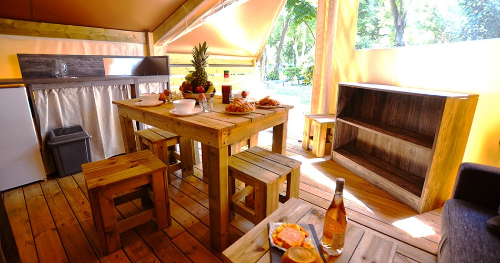 Interieur van Safari Tent Lodge Liberta bij Camping Merendella in Frankrijk, met houten meubels en eten.