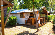 Tenda safari Tent Lodge Cottu al Camping Merendella in Francia con veranda in legno, immersa nel verde.