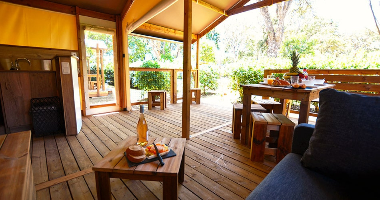 Interieur van safaritent Tent Lodge Cottu bij Camping Merendella in Frankrijk met houten terras en meubels.