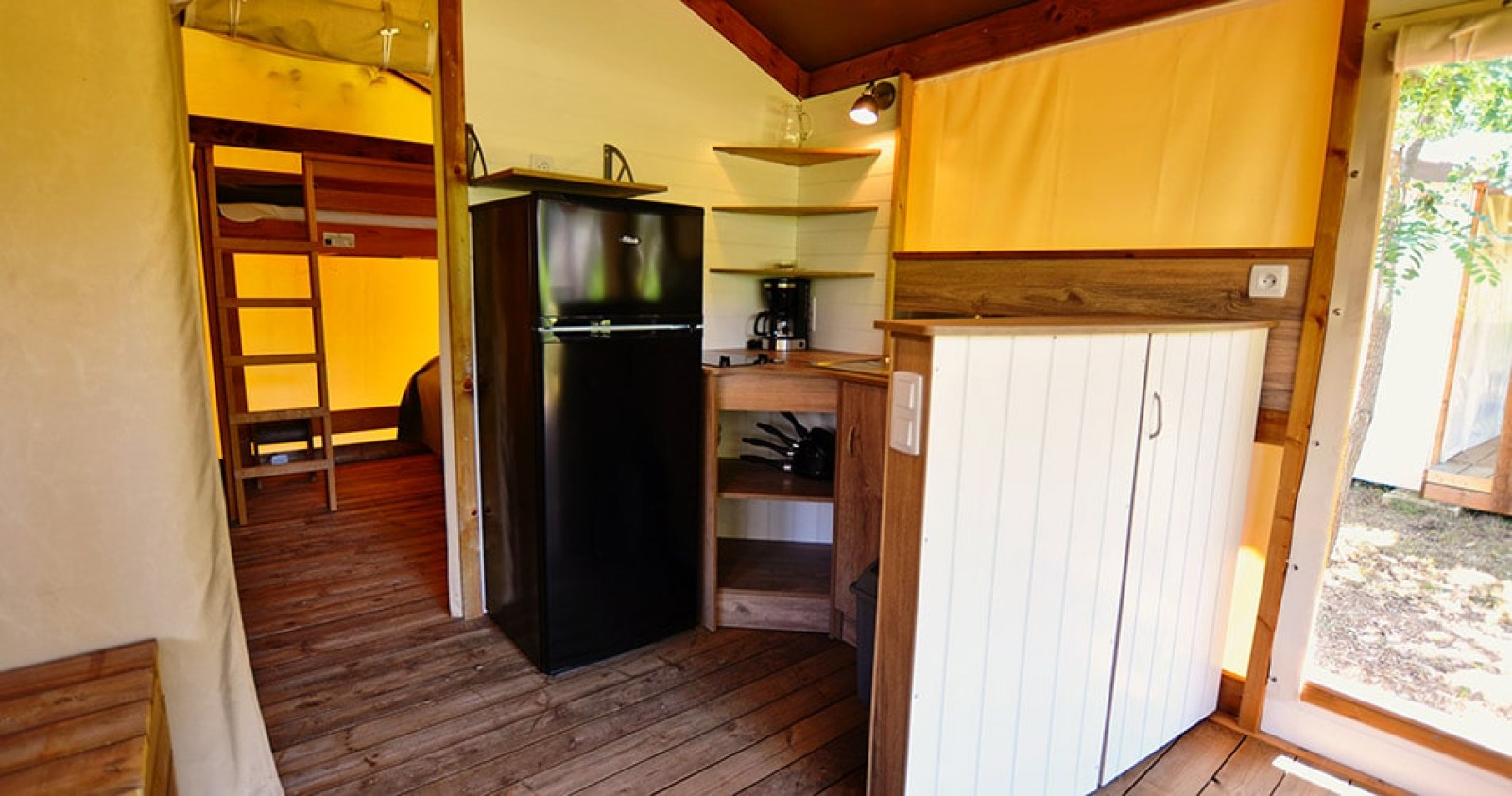 Interieur van safaritent Tent Lodge Cottu op Camping Merendella, met keuken en stapelbedden zichtbaar.