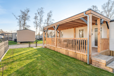 Vista esterna di Vakantiehuis Admiral al Camping Papillon in Belgio, con veranda e prato verde curato.