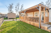 Vista esterna di Vakantiehuis Admiral al Camping Papillon in Belgio, con veranda e prato verde curato.