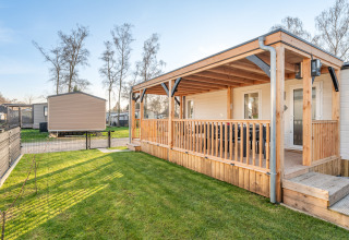 Vista esterna di Vakantiehuis Admiral al Camping Papillon in Belgio, con veranda e prato verde curato.