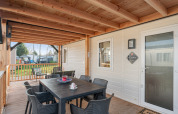 Veranda coperta del Vakantiehuis Admiral a Camping Papillon in Belgio, con tavolo da pranzo e sedie all’aperto.