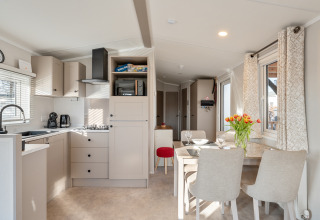 Cucina e zona pranzo luminose e moderne al Vakantiehuis Admiral al Camping Papillon, Belgio, con fiori sul tavolo.