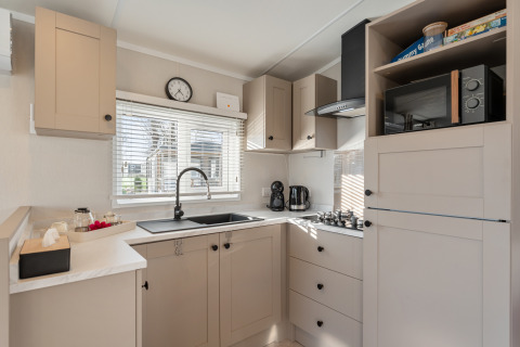 Cucina moderna con mobili chiari, piano cottura a gas, microonde e ampia finestra al Vakantiehuis Admiral, Belgio.