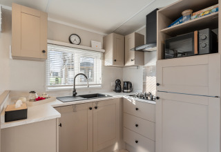 Cucina moderna con mobili chiari, piano cottura a gas, microonde e ampia finestra al Vakantiehuis Admiral, Belgio.
