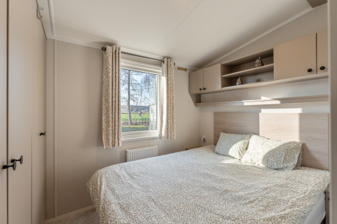 Camera da letto luminosa e moderna con letto matrimoniale, finestra e armadi in Vakantiehuis Admiral, Camping Papillon, Belgio.