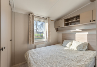 Camera da letto luminosa e moderna con letto matrimoniale, finestra e armadi in Vakantiehuis Admiral, Camping Papillon, Belgio.