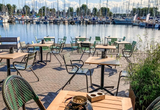 Außenterrasse mit Sitzplätzen und Blick auf einen Jachthafen bei Marina Parcs Naarden in den Niederlanden.