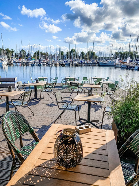 Udendørs café med udsigt over lystbådehavnen ved Marina Parcs Naarden, Holland, på en solrig dag.