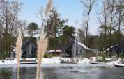 Ecovilla Waterzicht Comfort lodge at Holiday park Latour in the Netherlands, pond with fountain, snowy scenery.