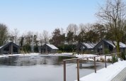 Vista invernale su Ecovilla Waterzicht Comfort, chalet sullo stagno al parco Latour, Paesi Bassi.