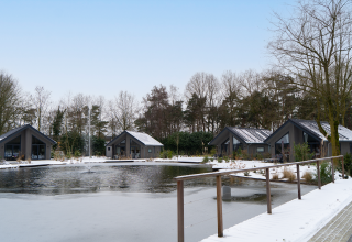 Winter view of Ecovilla Waterzicht Comfort lodges by a pond at Latour holiday park, Netherlands.