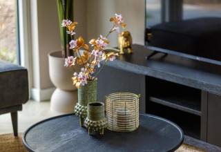 Modern coffee table with decorative green vases and candle at Ecovilla Waterzicht Comfort, Netherlands.