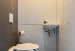Baño moderno con inodoro y lavabo en Ecovilla Waterzicht Comfort del Holiday park Latour, Países Bajos.