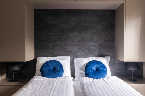 Camera moderna all'Ecovilla Waterzicht Comfort nei Paesi Bassi con letti gemelli e cuscini blu rotondi.