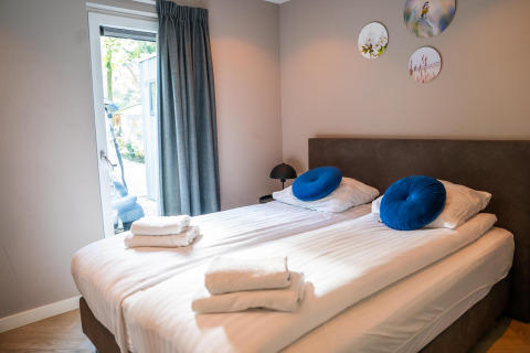 Modern bedroom with twin beds, blue cushions, decorative wall plates at Ecovilla Waterzicht Comfort, Netherlands.