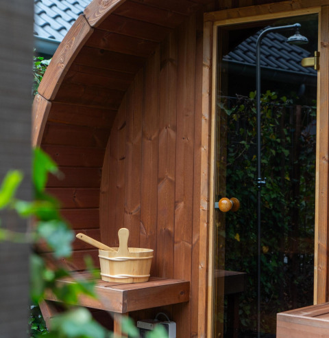 Outdoor wooden sauna with bucket and ladle at Ecovilla Waterzicht Comfort Sauna & Buitendouche in the Netherlands.