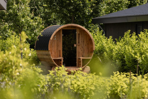 Sauna de barril en jardín verde de Ecovilla Waterzicht Comfort Sauna & Buitendouche, Holiday park Latour, Países Bajos.