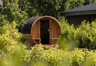 Sauna de barril en jardín verde de Ecovilla Waterzicht Comfort Sauna & Buitendouche, Holiday park Latour, Países Bajos.
