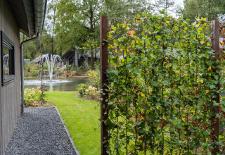 Vista su uno stagno con fontane, giardino e graticcio con rampicanti a Ecovilla Waterzicht in Olanda.