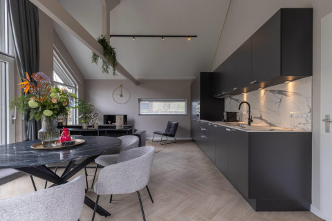 Cucina e zona pranzo moderne in Ecovilla Boszicht Comfort, con mobili neri e decorazioni floreali eleganti.