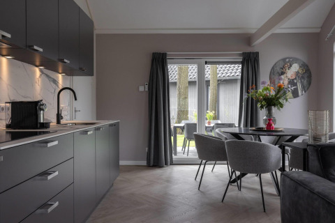 Cocina moderna y comedor en Ecovilla Boszicht Comfort del Holiday park Latour en Países Bajos, con vista al jardín.