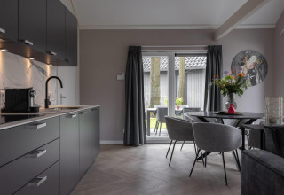 Cocina moderna y comedor en Ecovilla Boszicht Comfort del Holiday park Latour en Países Bajos, con vista al jardín.