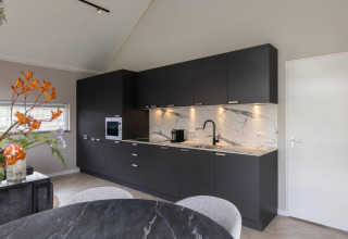 Modern kitchen at Ecovilla Boszicht Comfort, Holiday park Latour, Netherlands, with dark cabinetry.