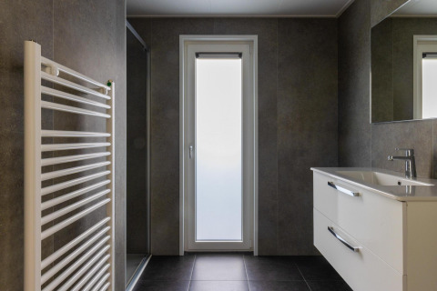 Modern bathroom with heated towel rack, sink, mirror and glass door in Villa Bosrand Comfort lodge.