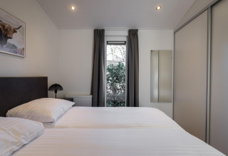 Bedroom at Villa Bosrand Comfort, Holiday park Latour, Netherlands, featuring twin beds and a bright window.