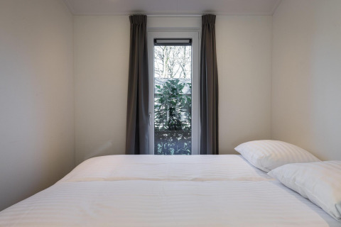 Camera minimalista a Villa Bosrand Comfort presso Holiday park Latour, Paesi Bassi, con finestra sul giardino.