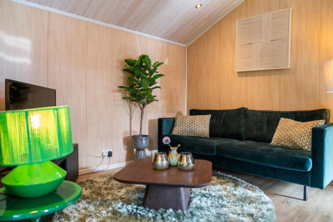 Living room at Lodge Deluxe Plus in Holiday park Latour, Netherlands, featuring green sofa and decor.