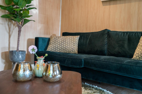 Salotto elegante nella Lodge Deluxe Plus presso Holiday park Latour, divano verde e cuscini decorativi.