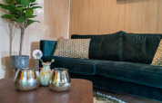 Salotto elegante nella Lodge Deluxe Plus presso Holiday park Latour, divano verde e cuscini decorativi.
