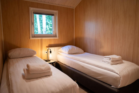 Camera da letto con due letti singoli e pannelli in legno nella Lodge Deluxe Plus al Holiday park Latour, Paesi Bassi.