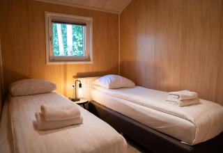 Camera da letto con due letti singoli e pannelli in legno nella Lodge Deluxe Plus al Holiday park Latour, Paesi Bassi.