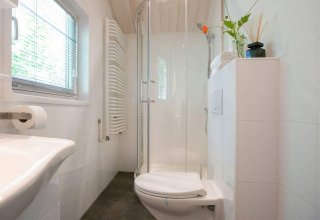 Modern bathroom with shower, toilet and window at Lodge Deluxe Plus, Holiday park Latour in the Netherlands.